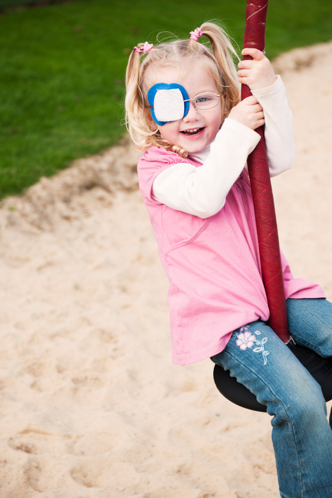 young girl with an eye patch for vision correction swinging on a flying fox style swing