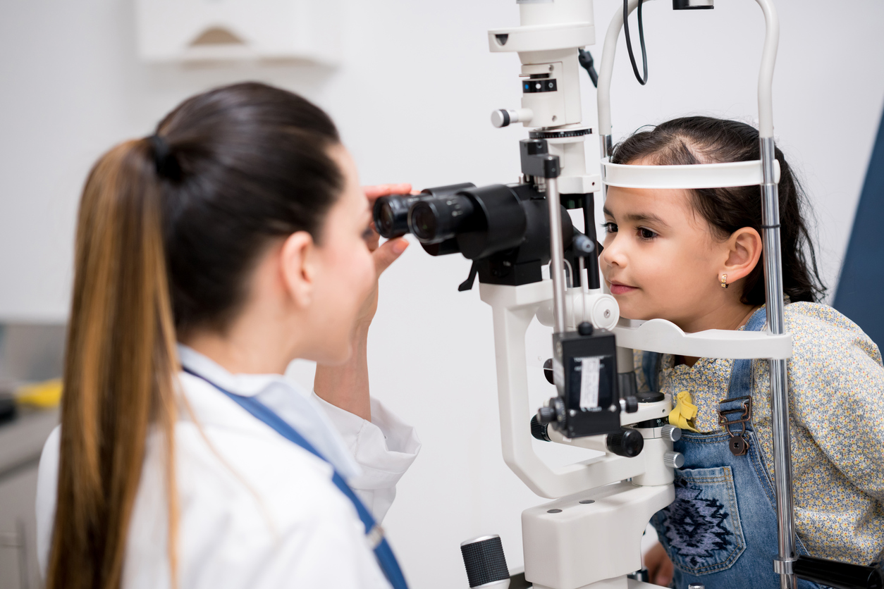 young hispanic girl having her eyes examined by a female optician