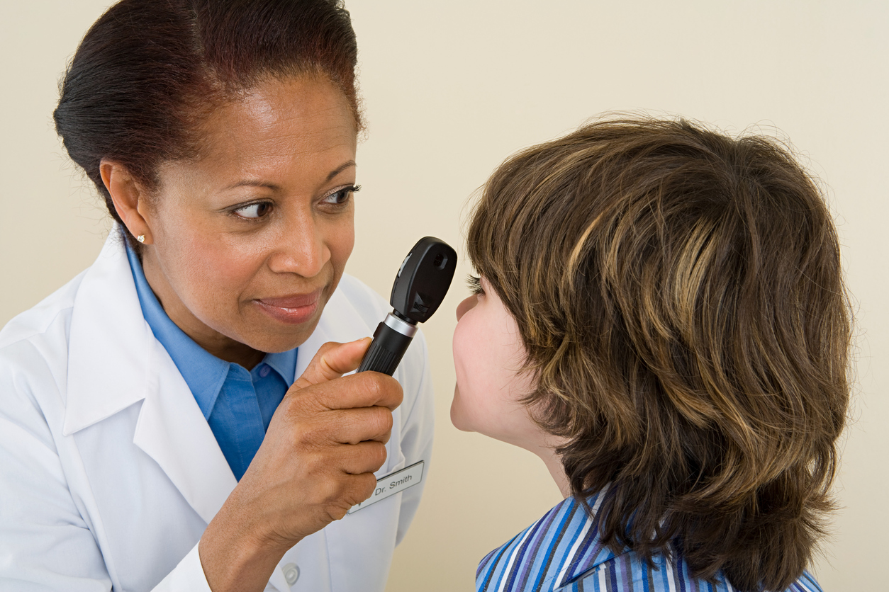 woman looking into a boy's eye with an eye exam tool